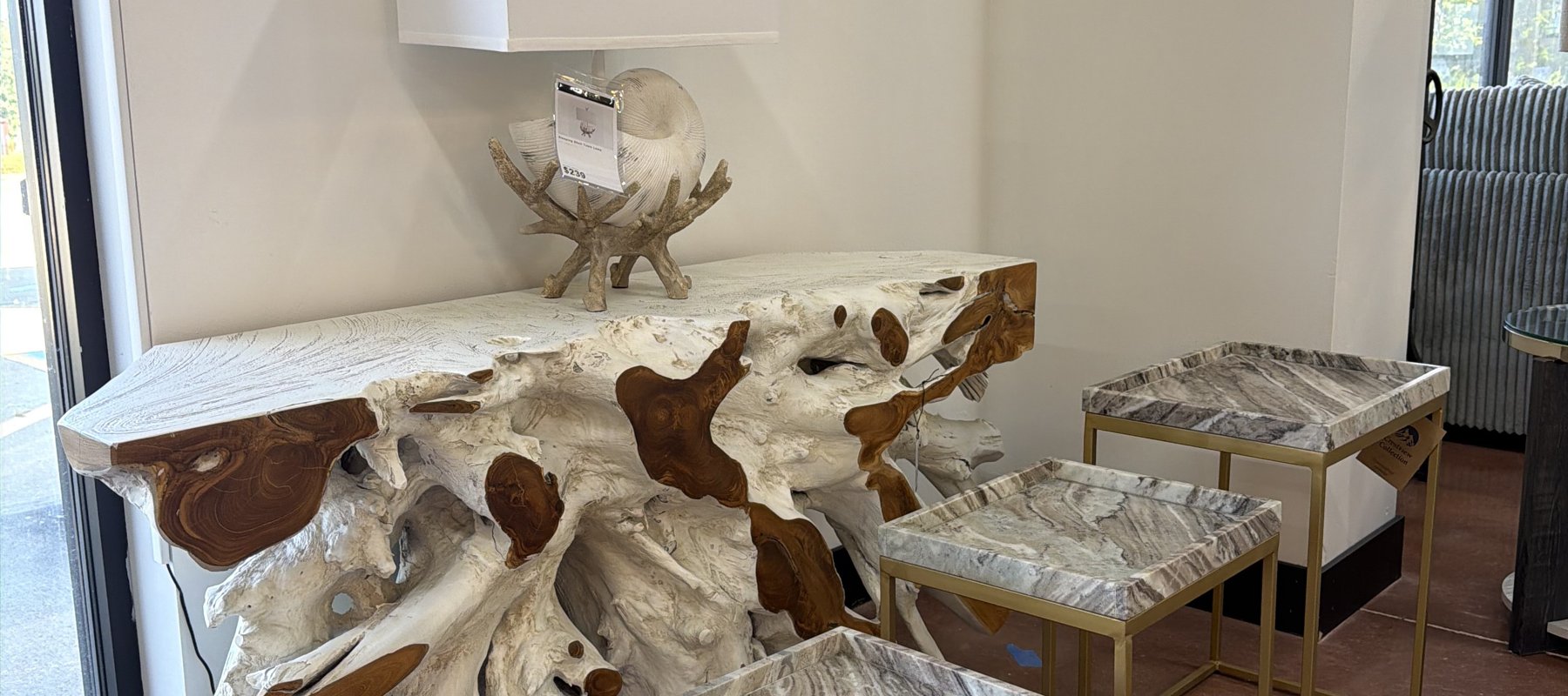 Live-edge petrified-wood console table with a natural wood sculpture and stone-topped side tables, a statement-piece vignette at Lakehouse Furniture Gallery in Osage Beach, Missouri.
