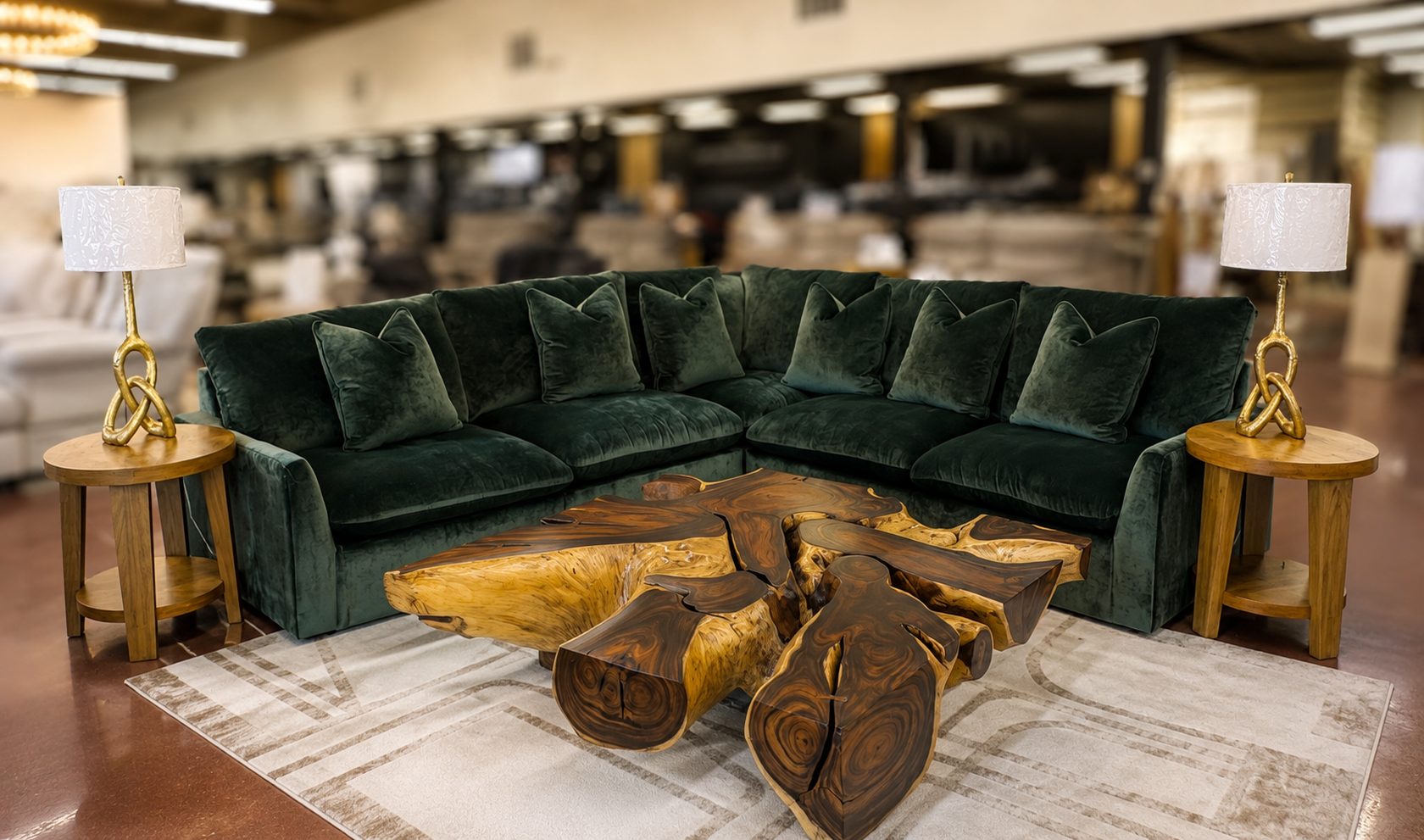 Inside Lakehouse Furniture Gallery in Osage Beach: a deep green velvet sectional with a sculptural live edge wood coffee table, styled on the gallery floor